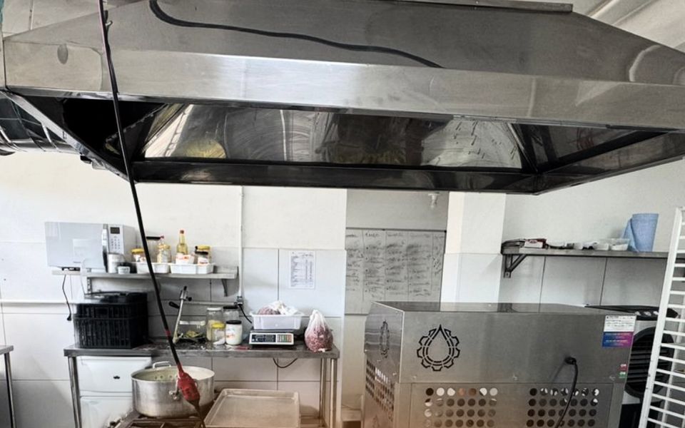 Cozinha de produção com coifa de inox, fogão industrial e máquina de inox