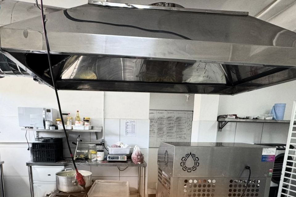 Cozinha de produção com coifa de inox, fogão industrial e máquina de inox