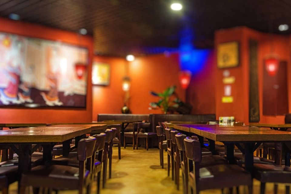 Salão de restaurante com mesas de madeira e paredes laranja